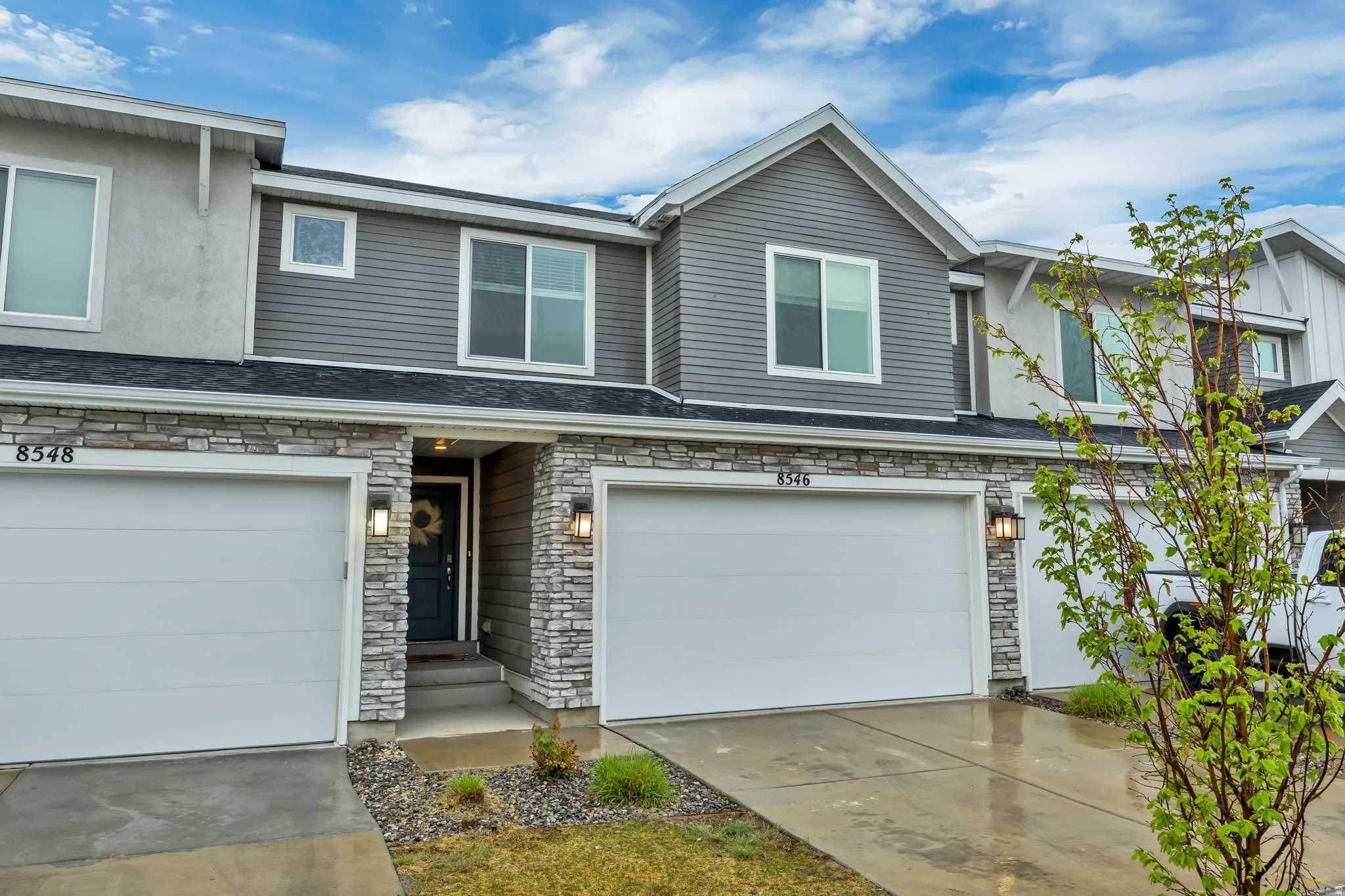 View of front of property featuring stone siding, an attached garage, and driveway