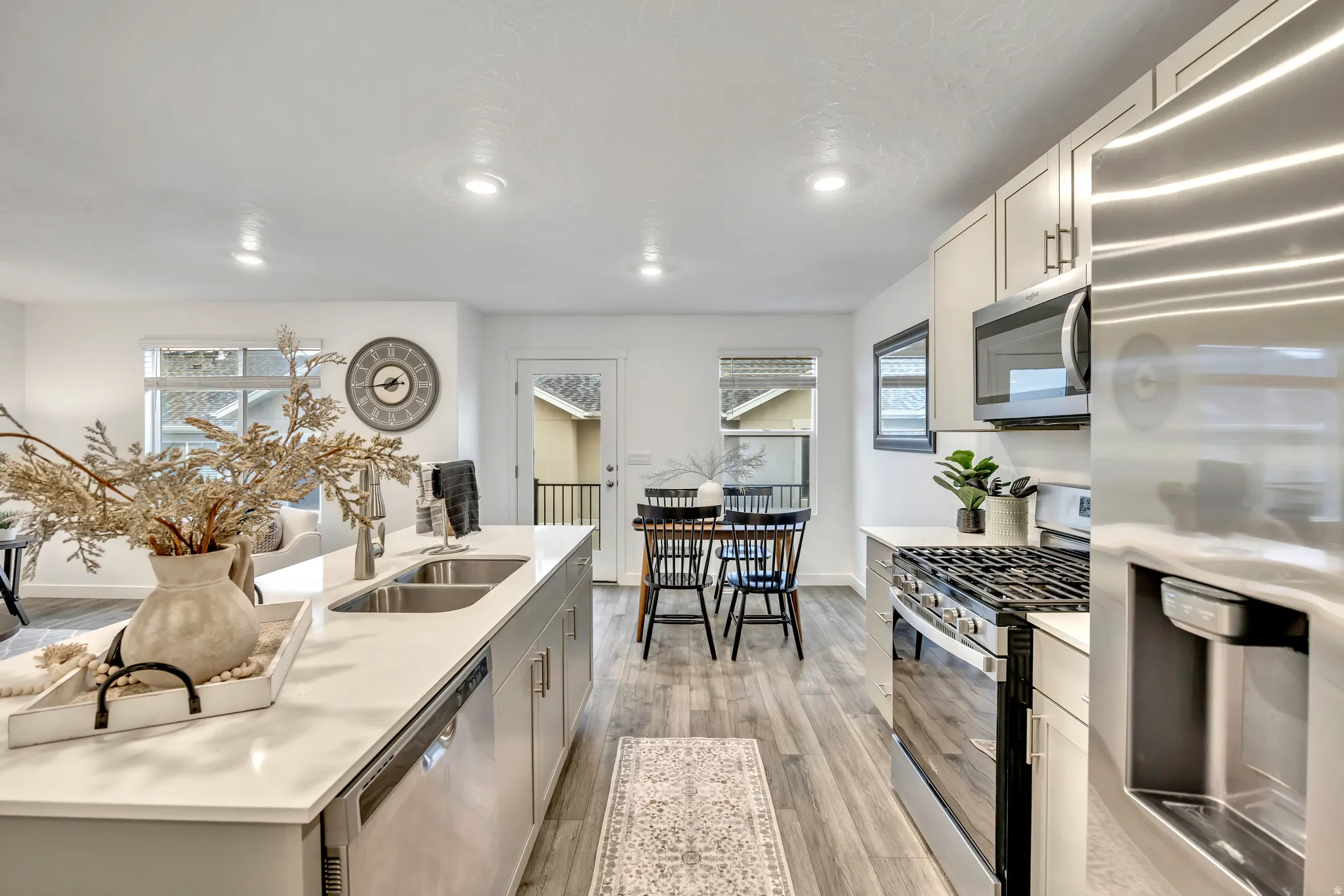 Kitchen with stainless steel appliances, light wood-style flooring, light stone countertops, gray cabinetry, and recessed lighting