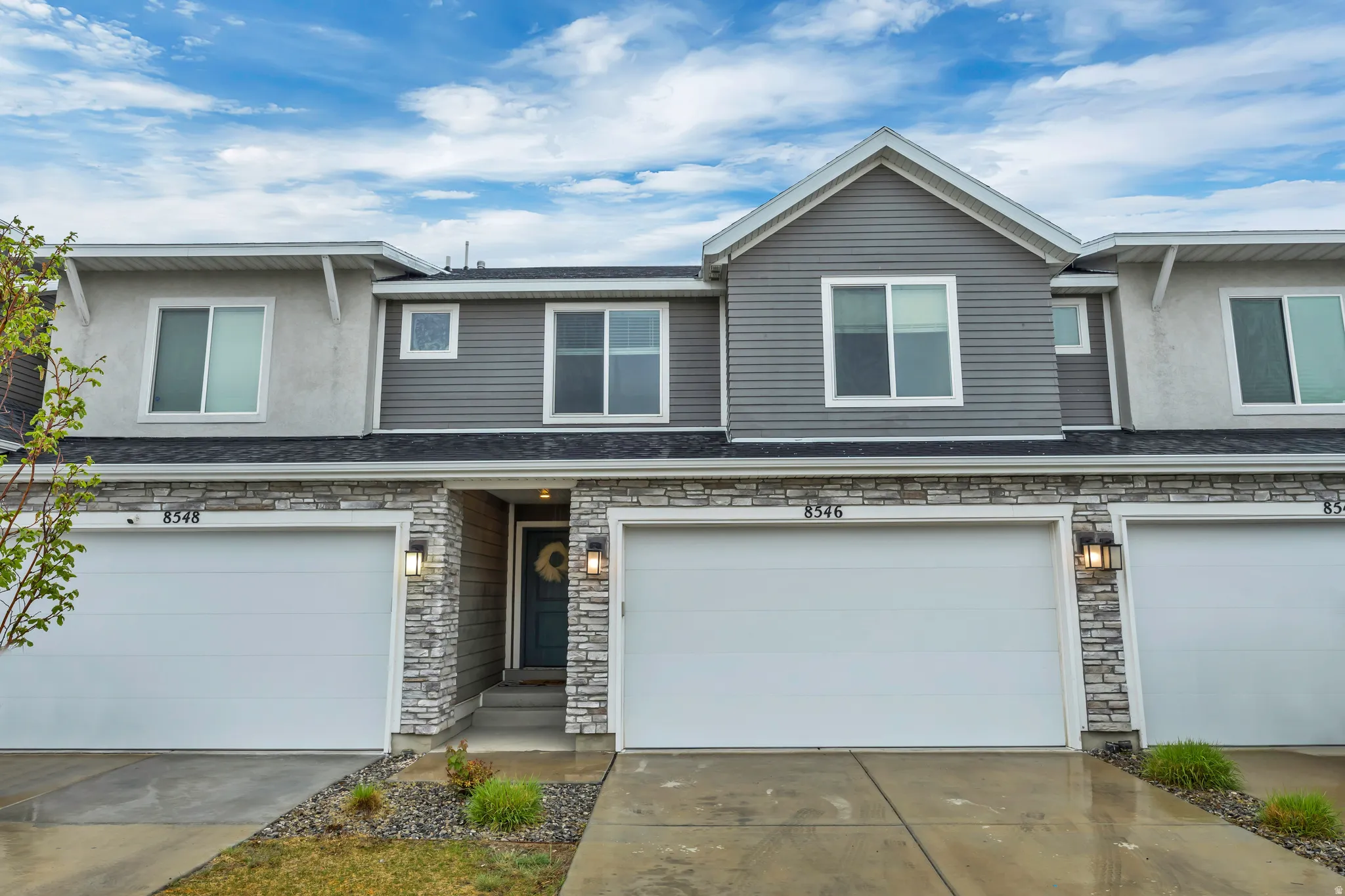 View of front of home featuring stone siding, a garage, driveway, and stucco siding