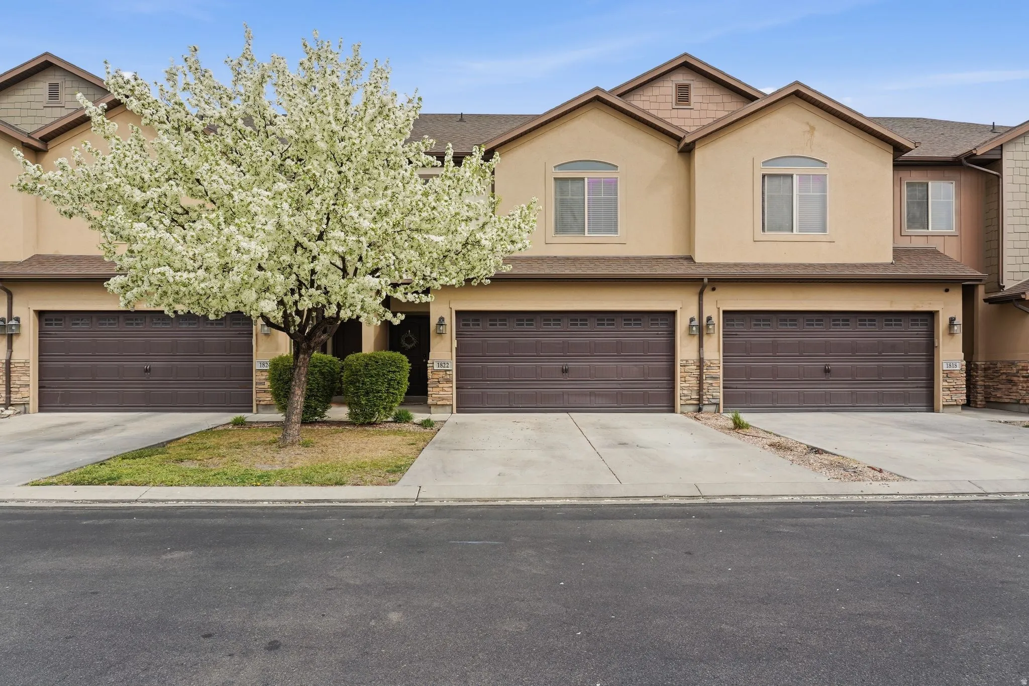 View of front facade featuring concrete driveway, stucco siding, a garage, and stone siding