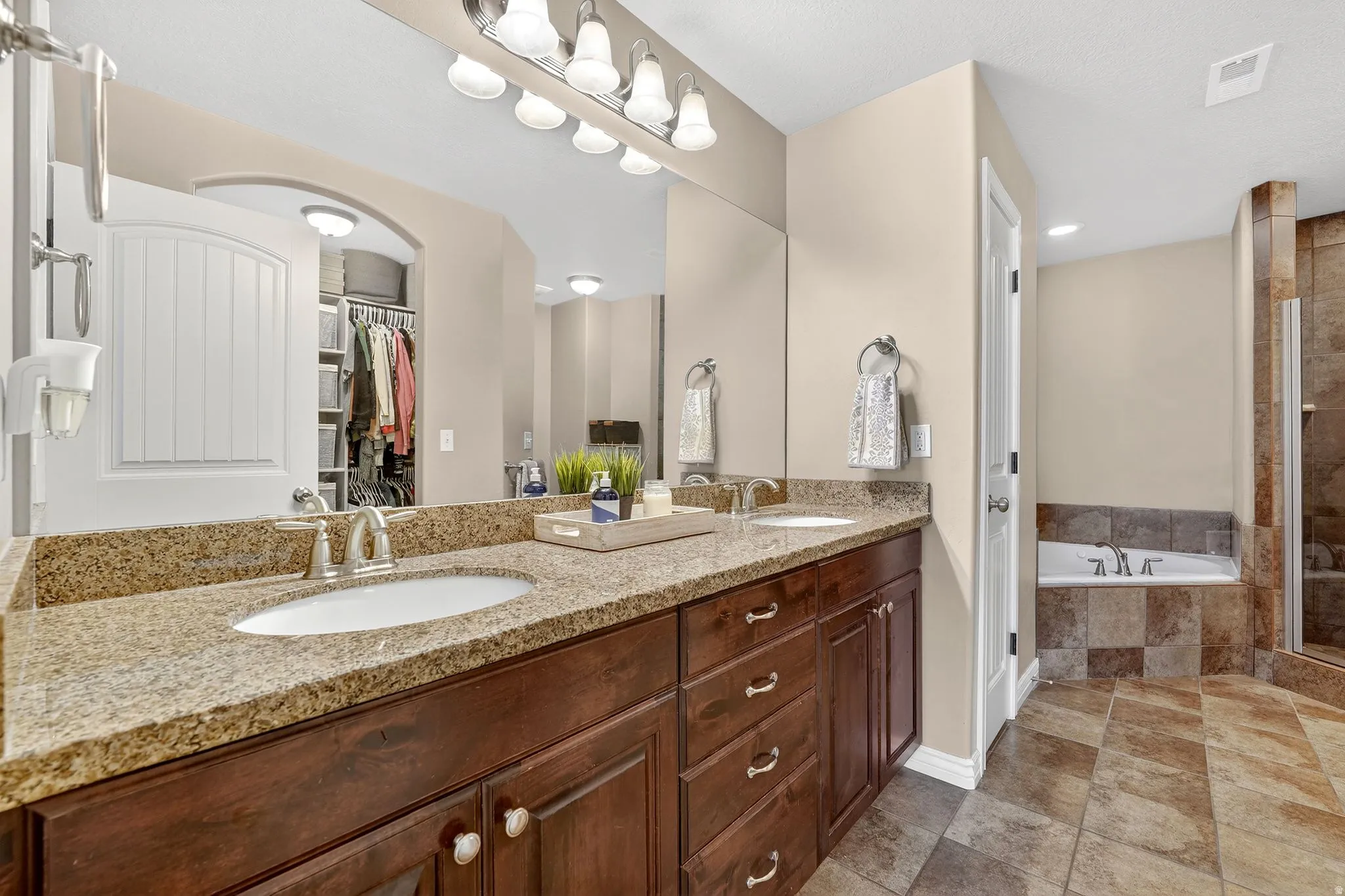 Bathroom with double vanity, a garden tub, a shower stall, and a walk in closet