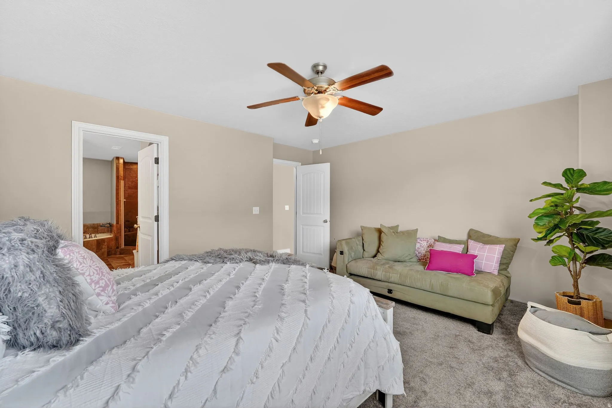 Carpeted bedroom featuring connected bathroom and a ceiling fan