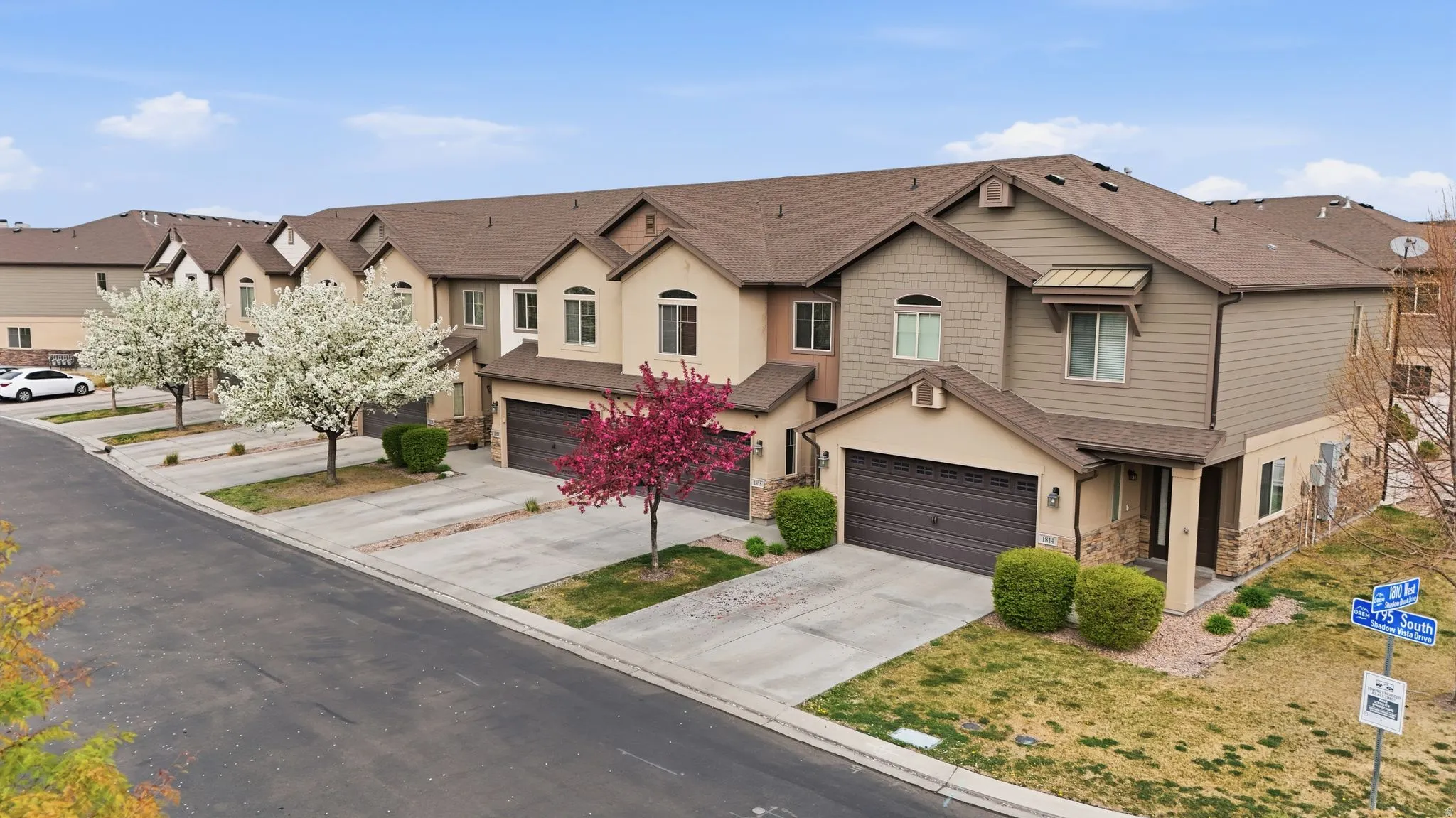 View of front of property featuring concrete driveway, stone siding, a residential view, an attached garage, and roof with shingles
