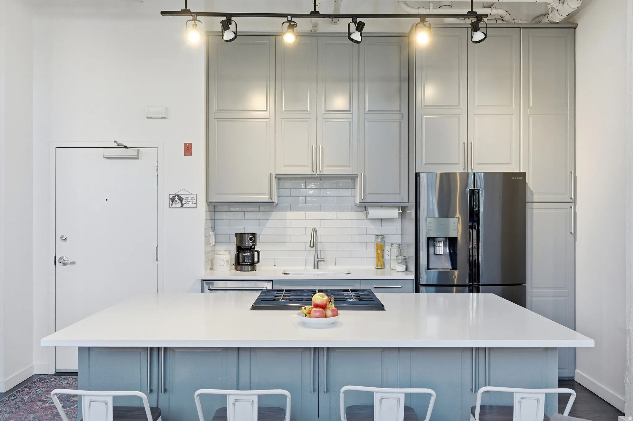 Kitchen with stainless steel appliances, gray cabinets, and light stone counters
