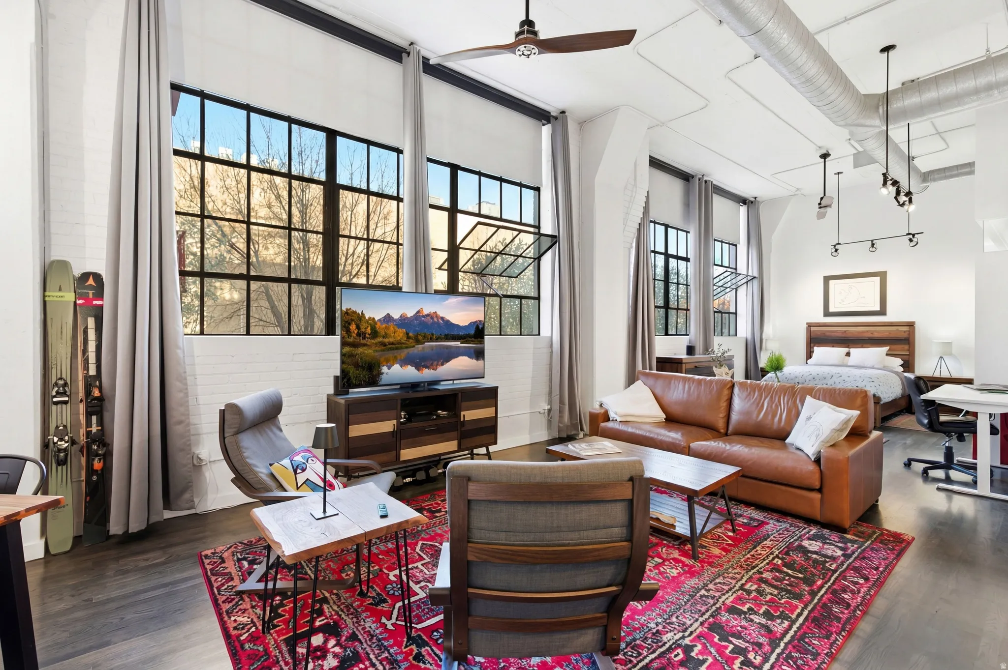 Living area featuring a ceiling fan, dark wood-type flooring, and a high ceiling