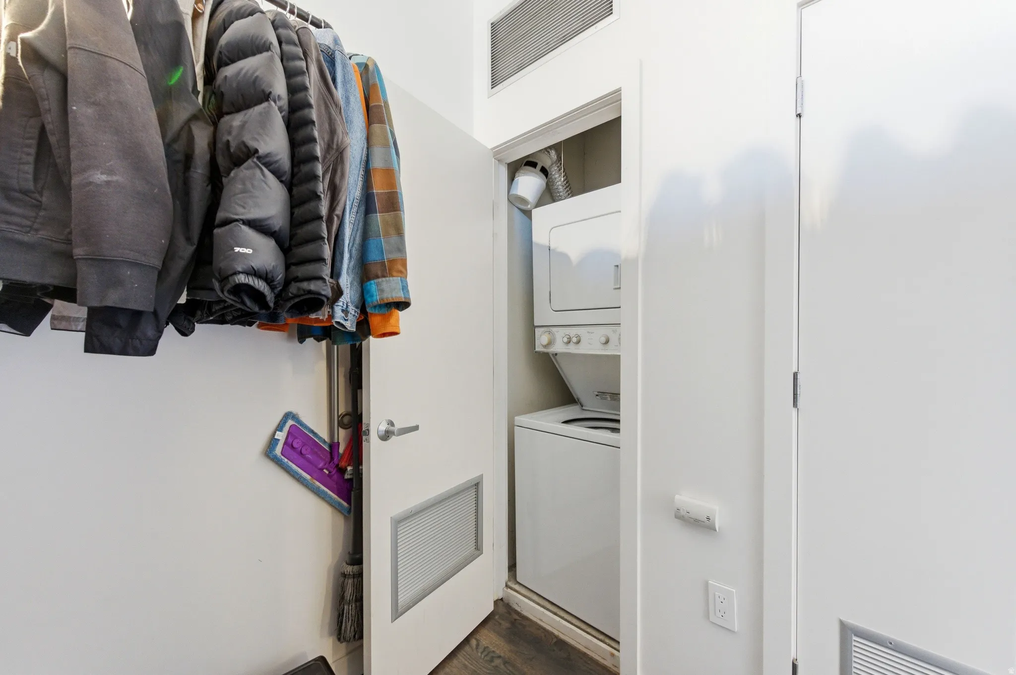 Laundry area featuring stacked washer and clothes dryer and dark wood-type flooring