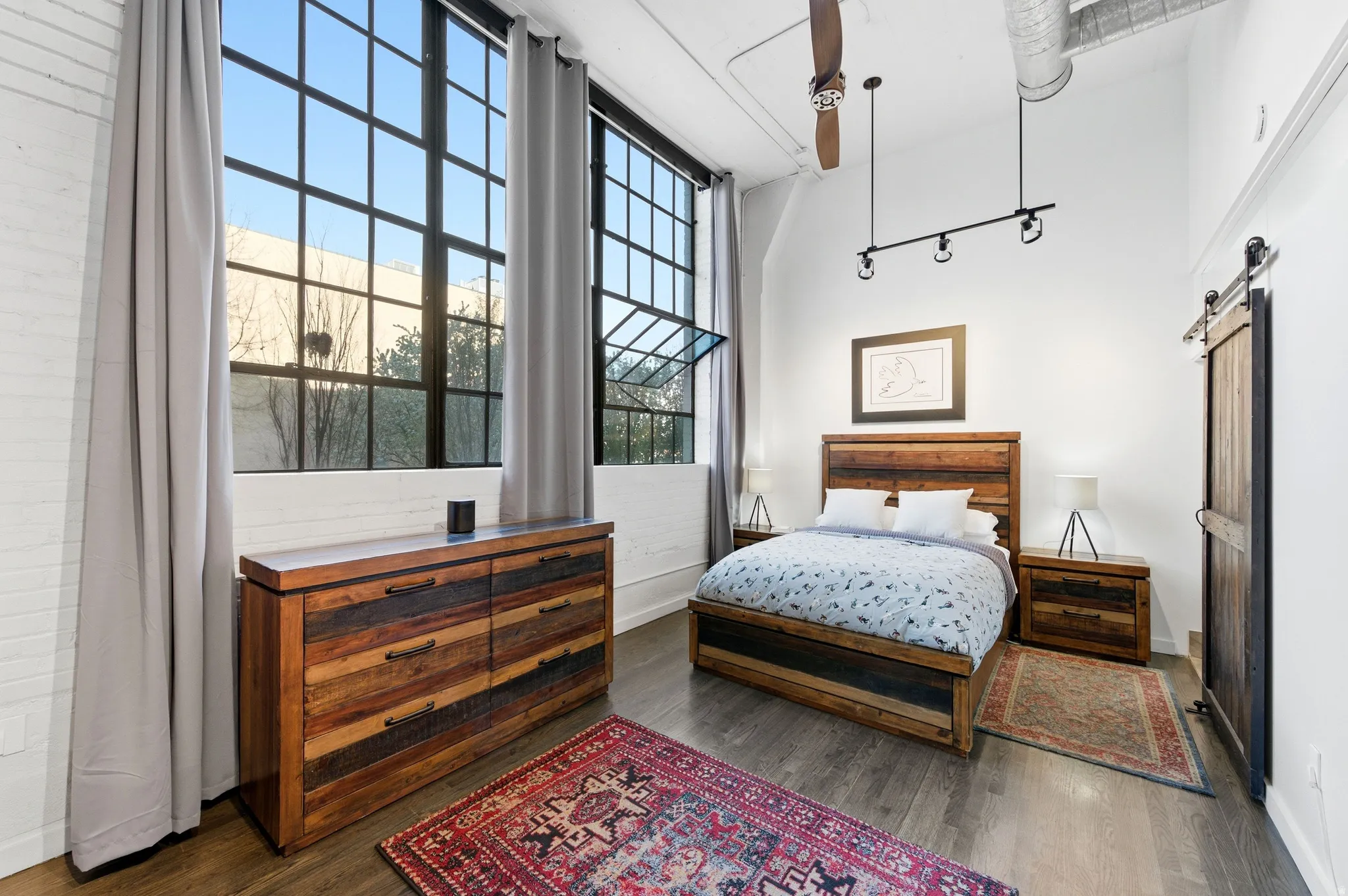 Bedroom featuring a barn door, dark wood finished floors, and a high ceiling