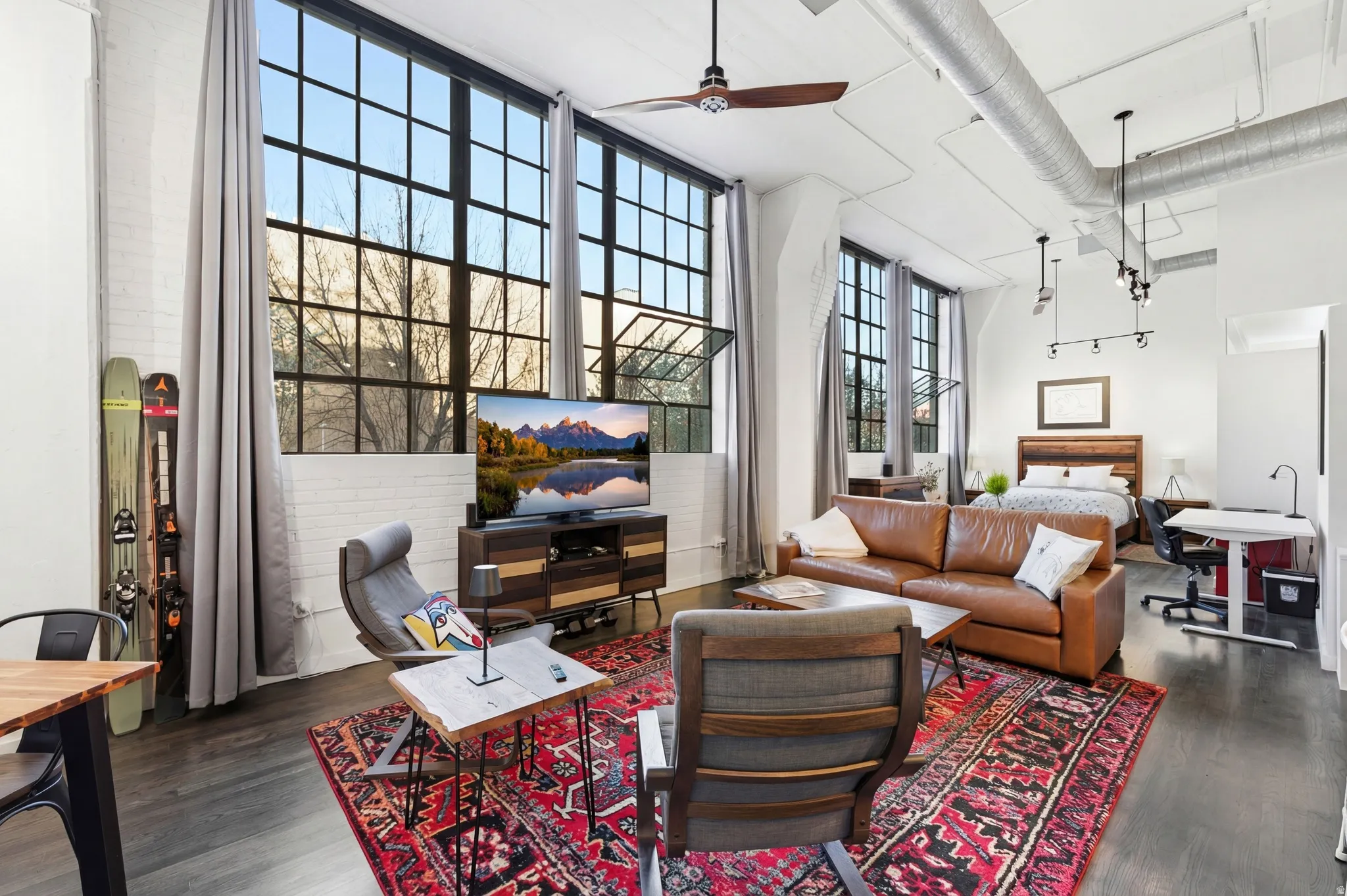 Living area featuring a ceiling fan, a high ceiling, and dark wood-style floors