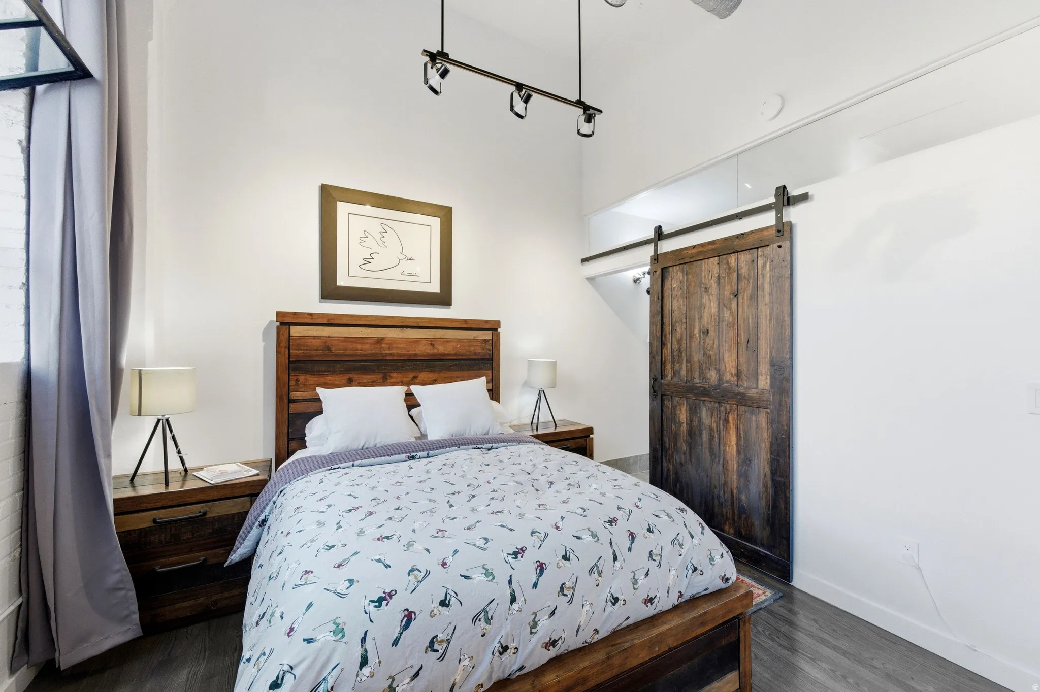 Bedroom featuring a barn door and dark wood-style floors