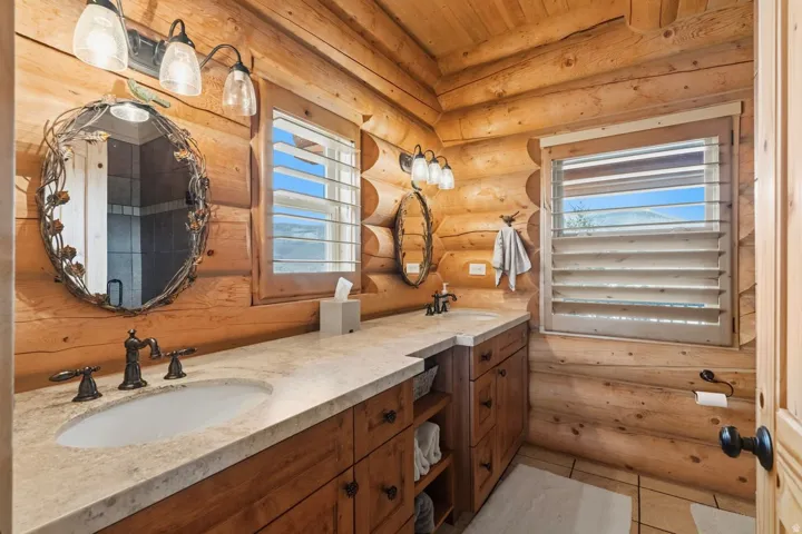 Bathroom featuring rustic walls, double vanity, light tile patterned floors, and wooden ceiling
