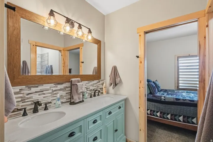 Ensuite bathroom with double vanity, carpet floors, and decorative backsplash