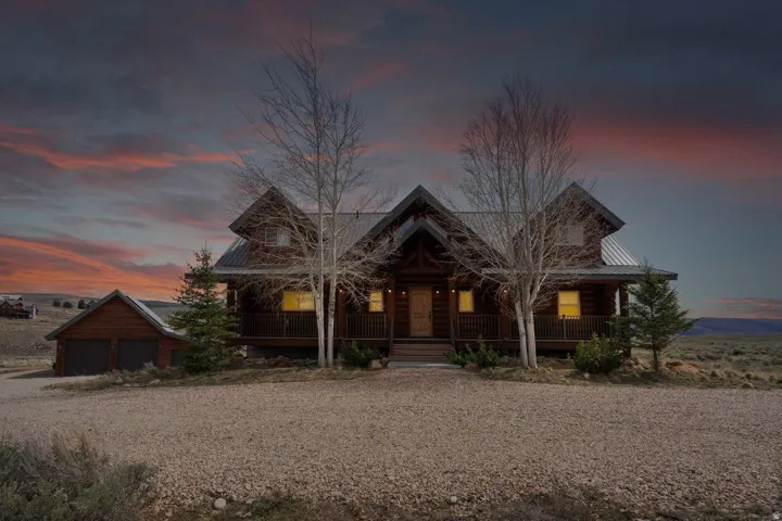 Chalet / cabin featuring covered porch, gravel driveway, and a detached garage