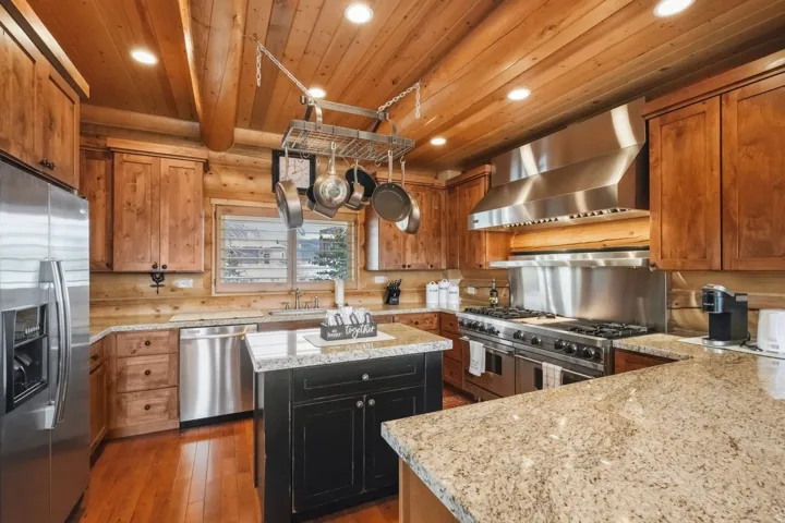 Kitchen featuring light stone countertops, stainless steel appliances, dark wood-style floors, a center island, and recessed lighting
