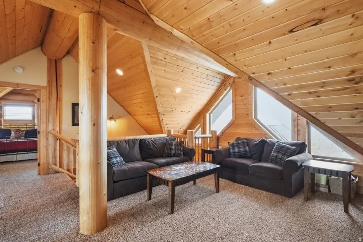 Living room featuring a wooden ceiling with exposed beams and carpet floors