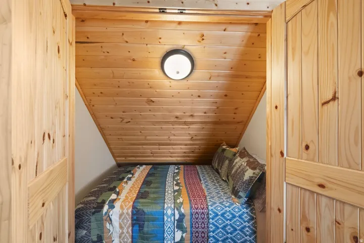 Bedroom with a vaulted wooden ceiling and a closet