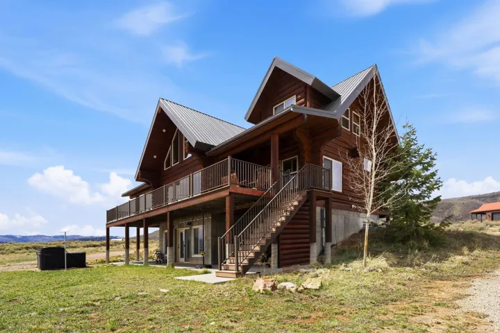 Rear view of property featuring a metal roof, a mountain view, a yard, and log exterior