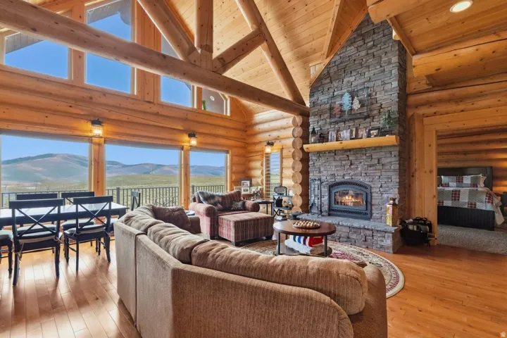 Living area with rustic walls, a stone fireplace, a mountain view, hardwood / wood-style floors, and a high wood beamed ceiling