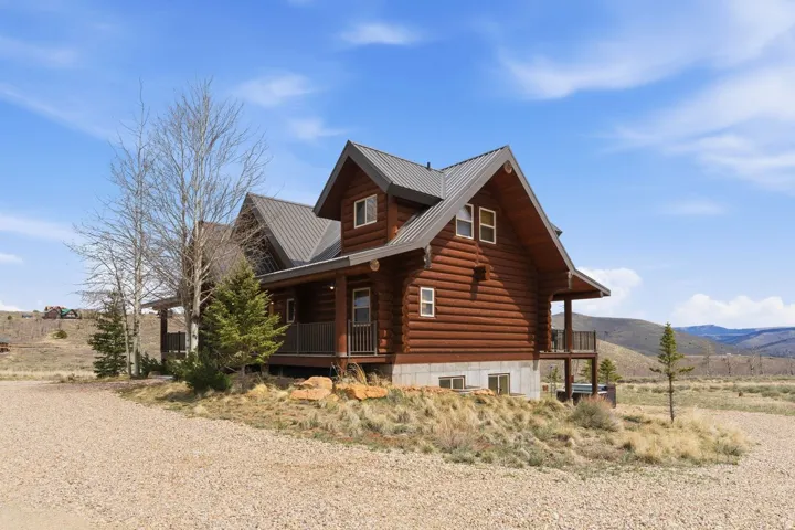 View of property exterior with a porch, log exterior, a metal roof, and a mountain view
