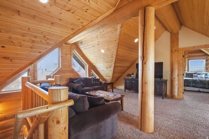 Carpeted living room with a wood ceiling with exposed beams and recessed lighting