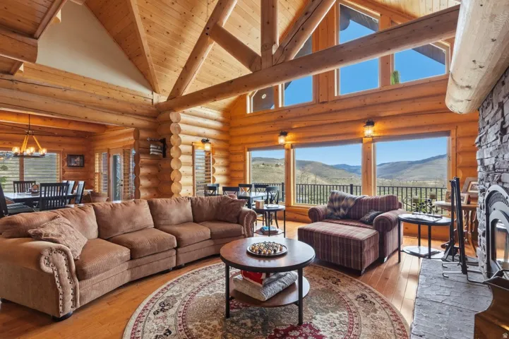Living room with light wood finished floors, a mountain view, healthy amount of natural light, log walls, and a chandelier