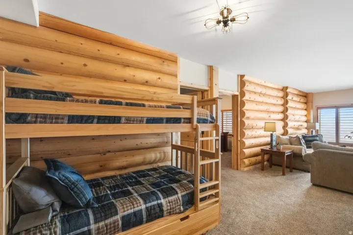 Bedroom featuring log walls, light carpet, and multiple windows