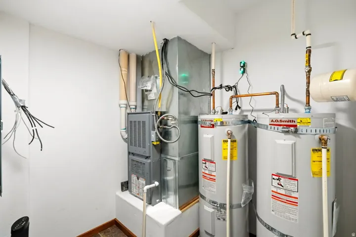 Utility room featuring secured water heater and heating unit