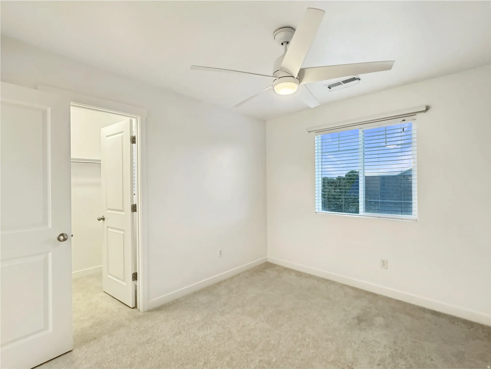 Empty room featuring light colored carpet and ceiling fan