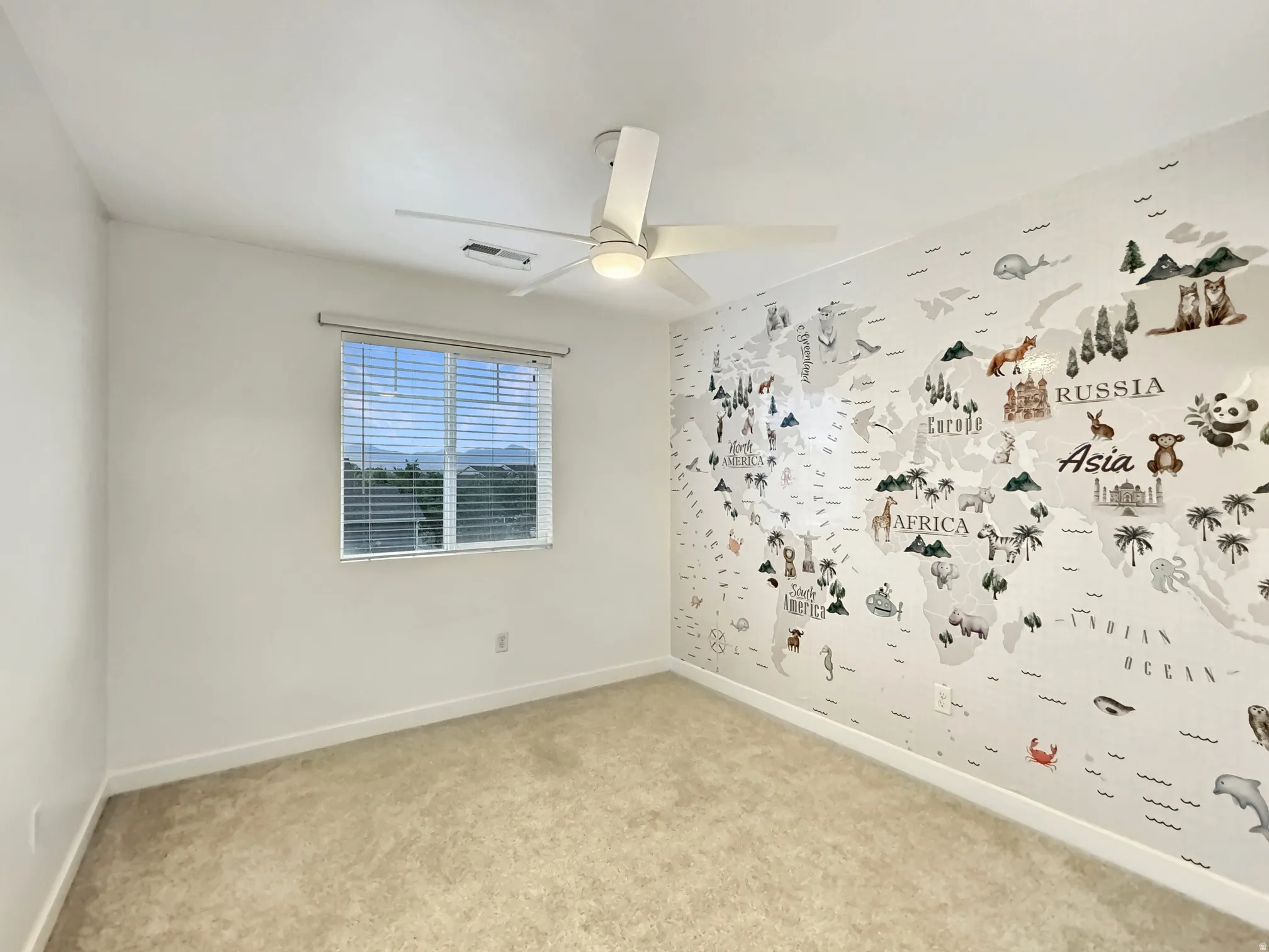 Carpeted empty room with baseboards and a ceiling fan