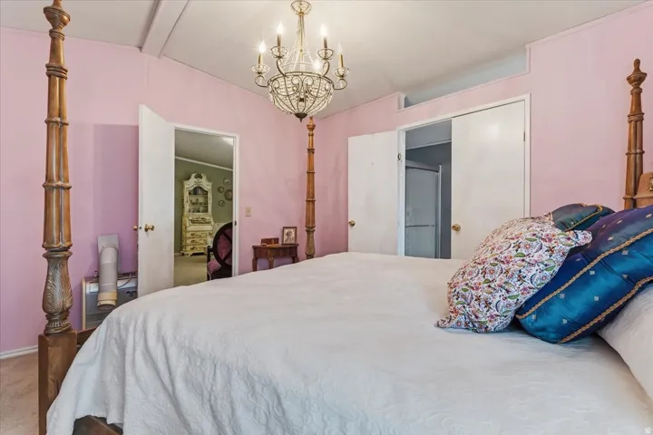 Primary bedroom, vaulted ceiling with beams, and carpet flooring
