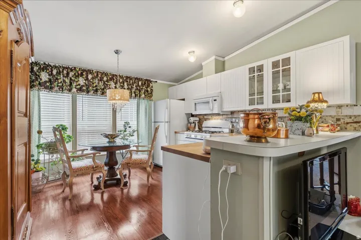 Kitchen featuring glass insert cabinets, decorative backsplash, lofted ceiling, white cabinetry,  butcher block countertops