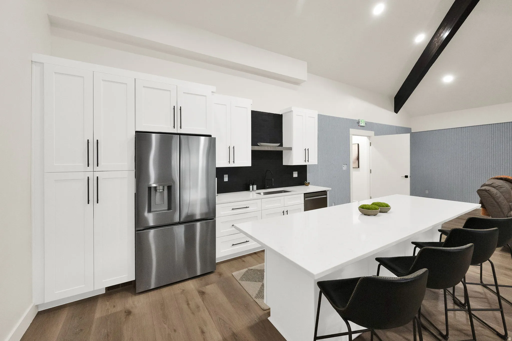 Kitchen featuring stainless steel appliances, dark wood-type flooring, a kitchen island, a breakfast bar area, and white cabinetry