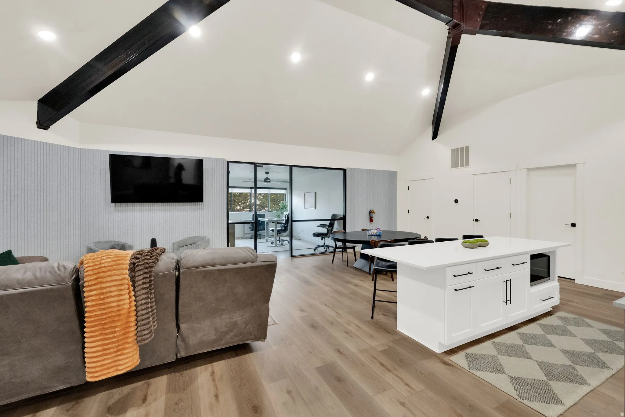 Living area with light wood-style floors, vaulted ceiling, and recessed lighting