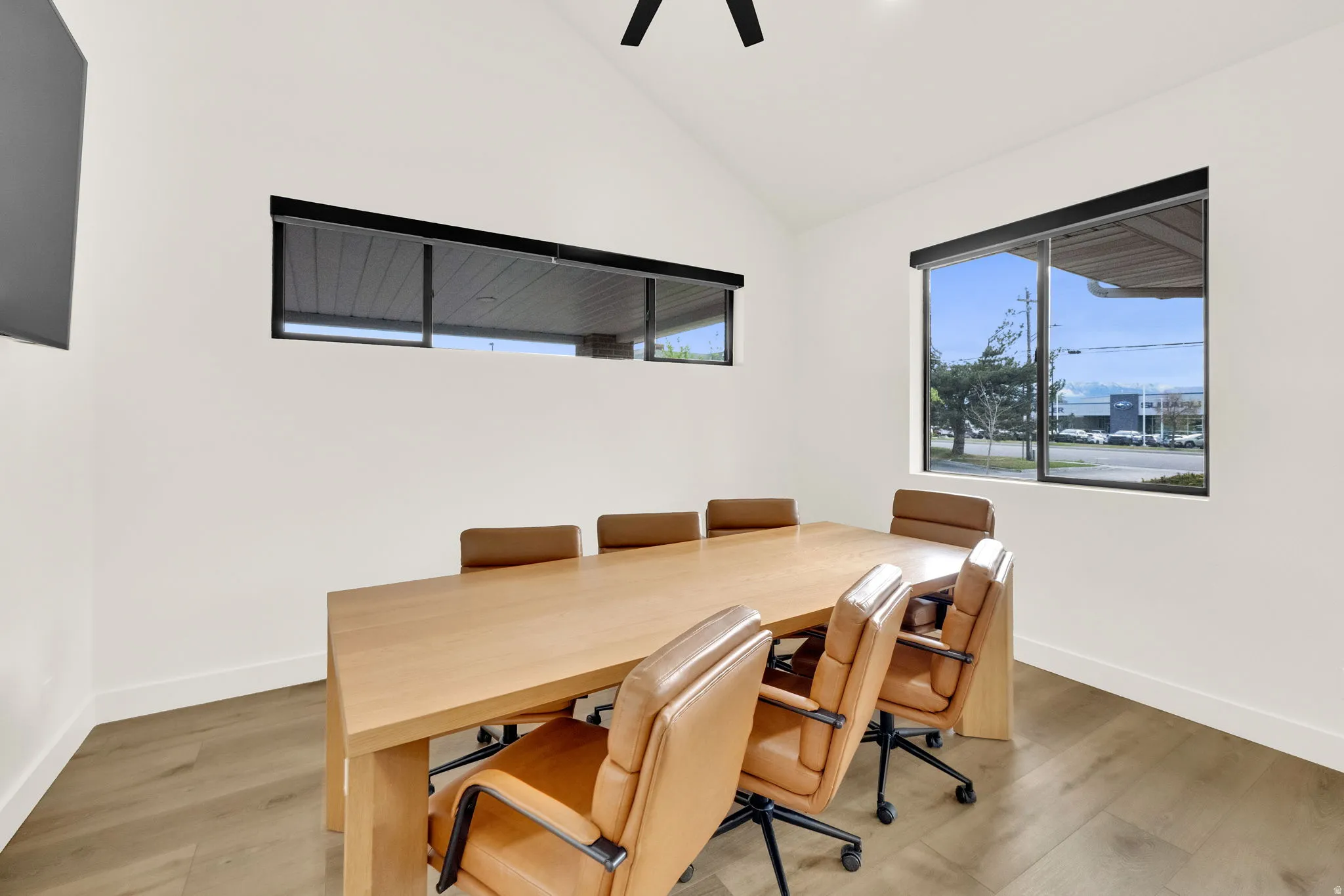 Home office with light wood-style flooring, lofted ceiling, and ceiling fan