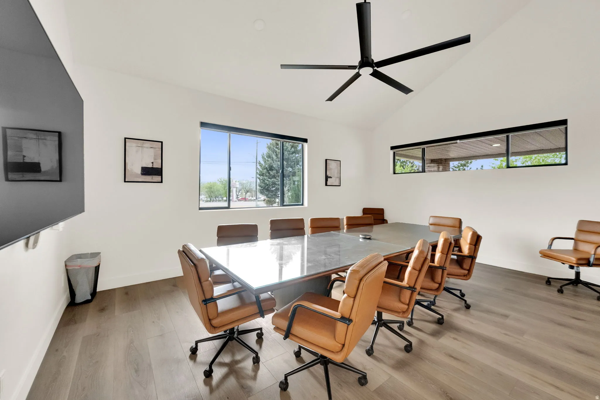 Dining room with light wood finished floors, vaulted ceiling, and a ceiling fan