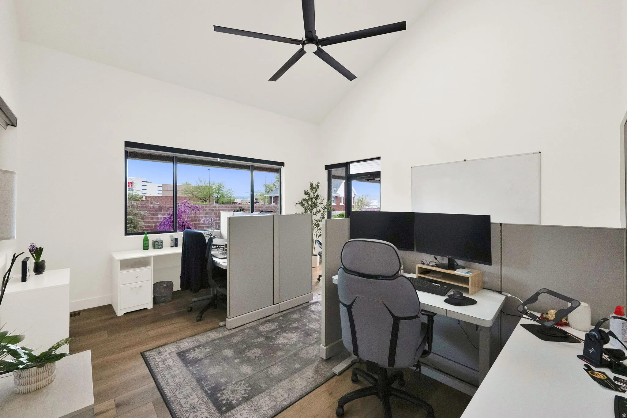 Office area featuring dark wood-style floors, vaulted ceiling, and a ceiling fan