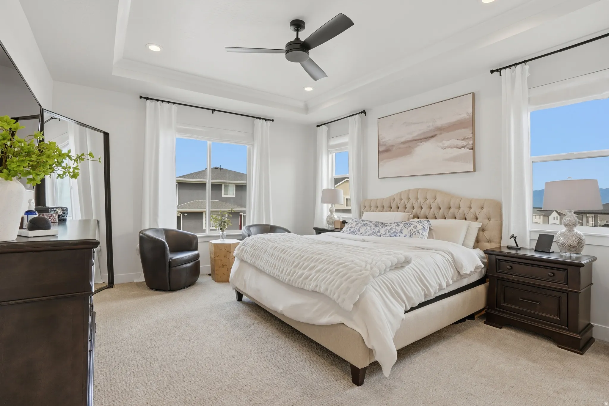 Bedroom with recessed lighting, light carpet, ceiling fan, and a tray ceiling