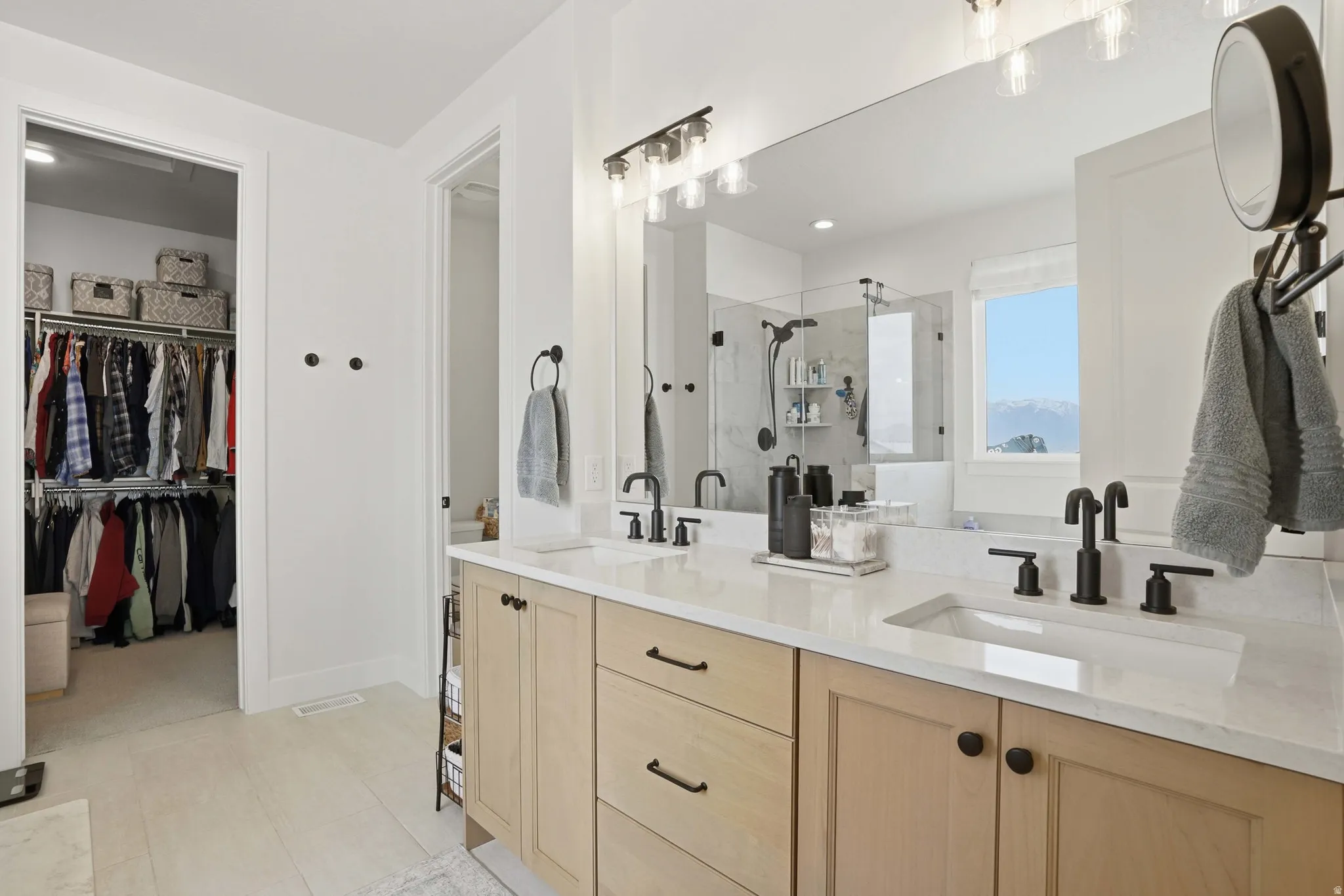 Full bathroom featuring double vanity, a stall shower, and a walk in closet