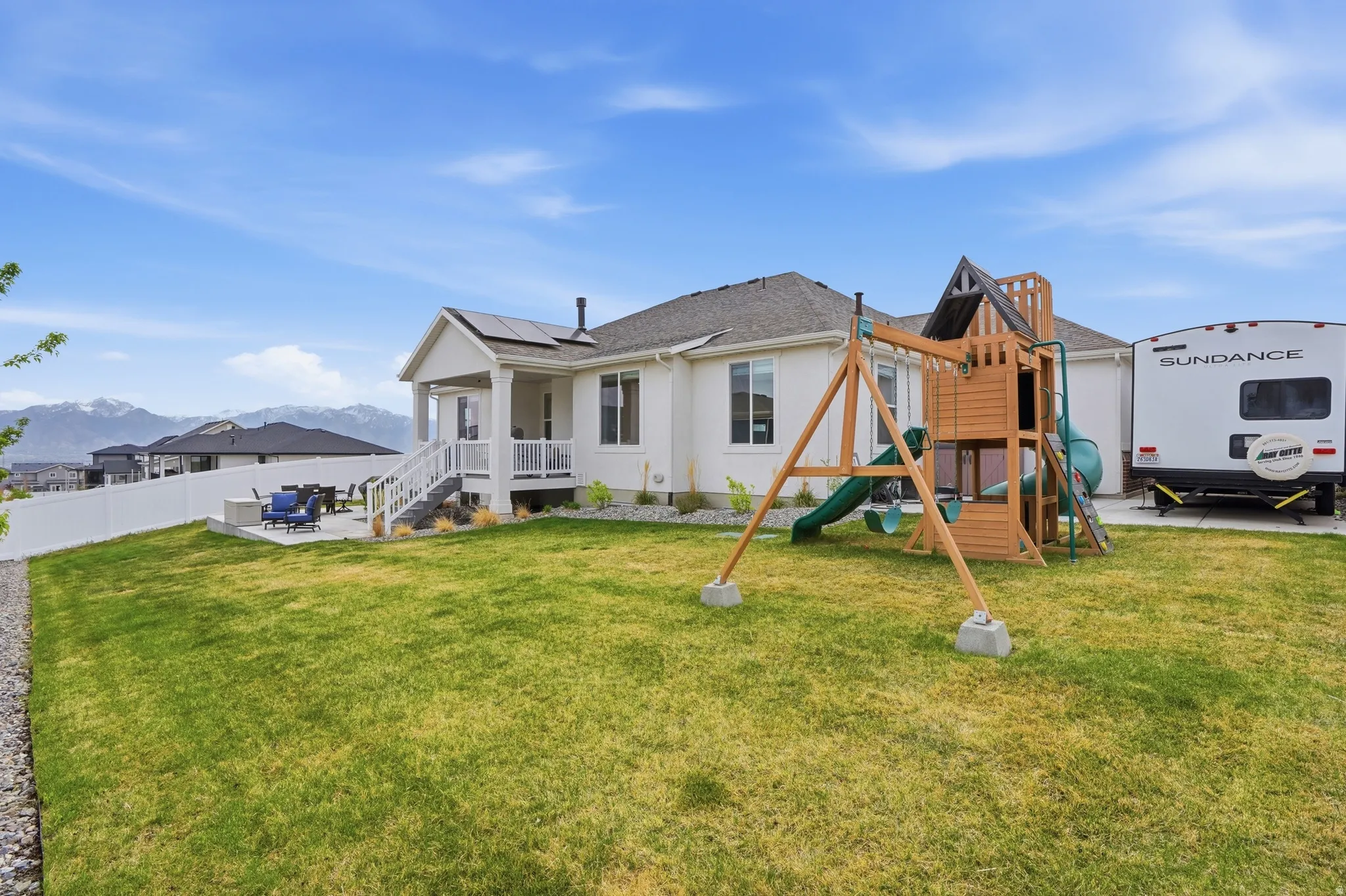 Rear view of property featuring a patio area, roof mounted solar panels, a playground, a mountain view, and stucco siding