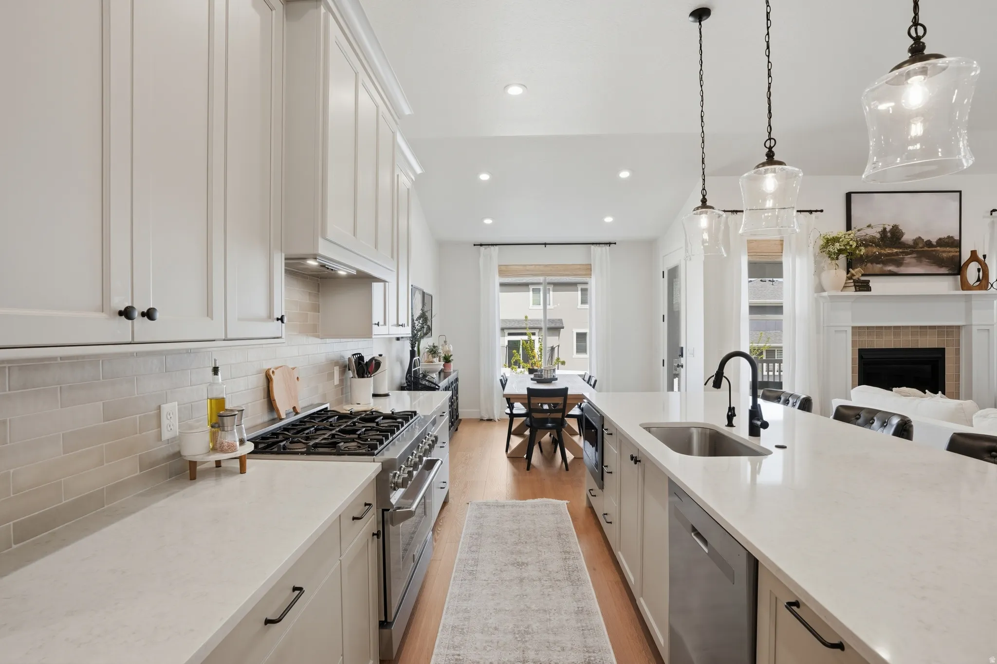 Kitchen with stainless steel appliances, white cabinets, a fireplace, light wood-type flooring, and light stone counters