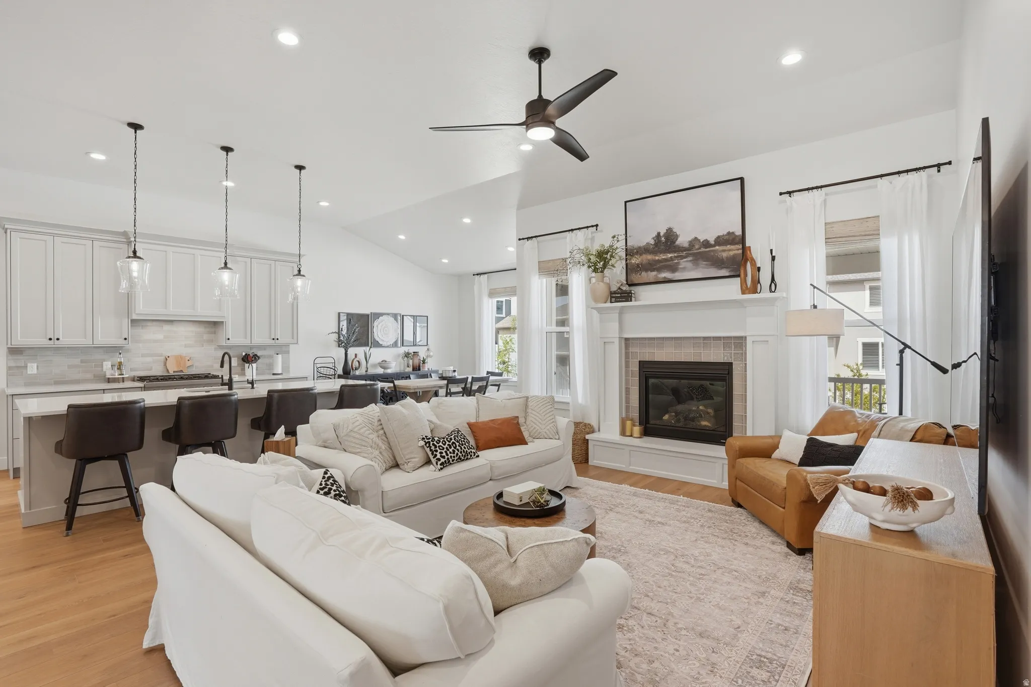 Living room featuring vaulted ceiling, a tile fireplace, a ceiling fan, light wood-type flooring, and recessed lighting