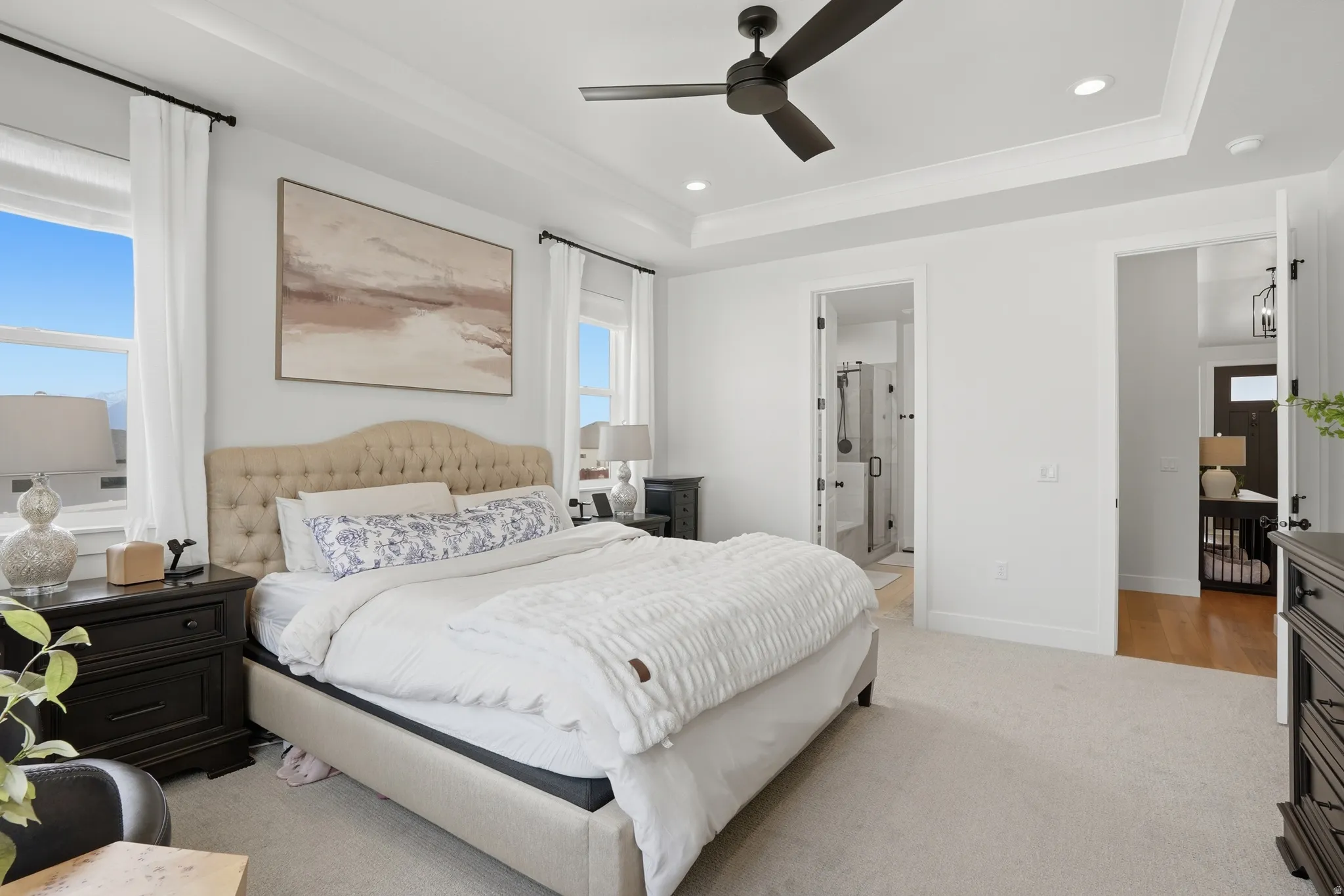 Bedroom featuring a tray ceiling, light carpet, recessed lighting, a ceiling fan, and ensuite bathroom