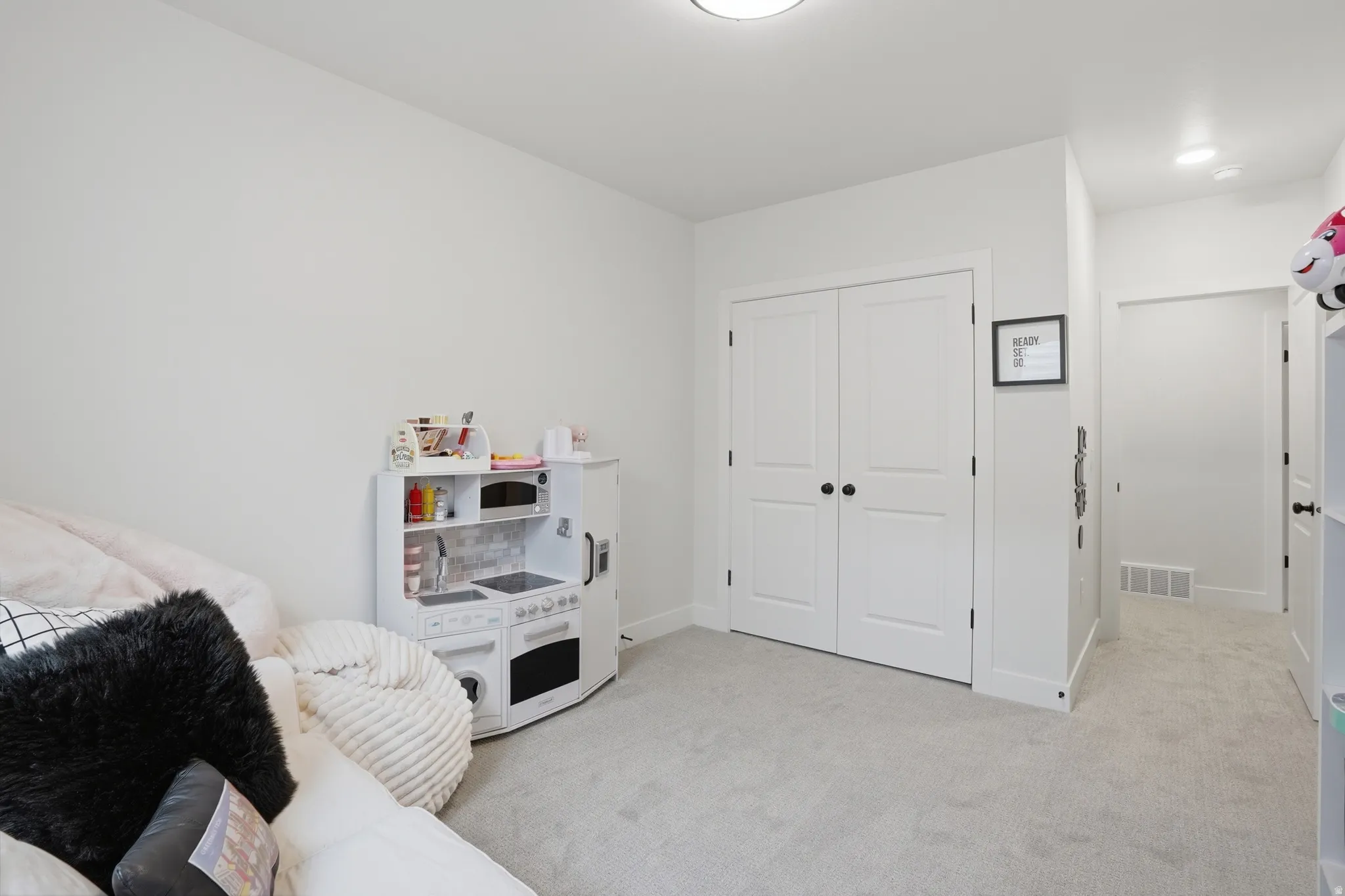 Bedroom with light colored carpet and a closet