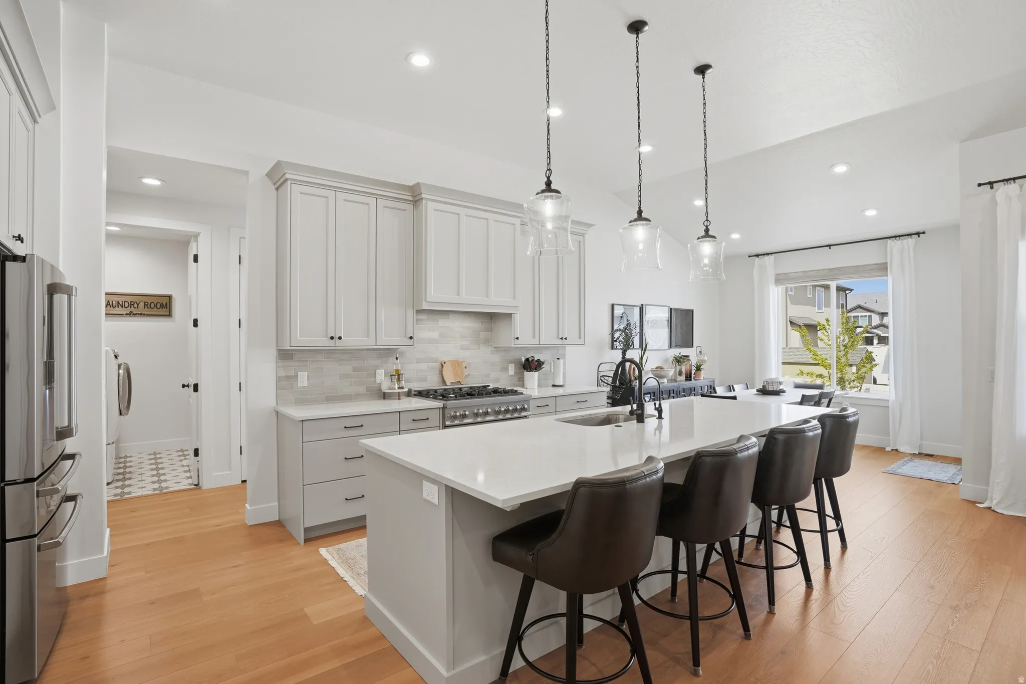 Kitchen with freestanding refrigerator, a kitchen bar, an island with sink, light wood-style floors, and vaulted ceiling