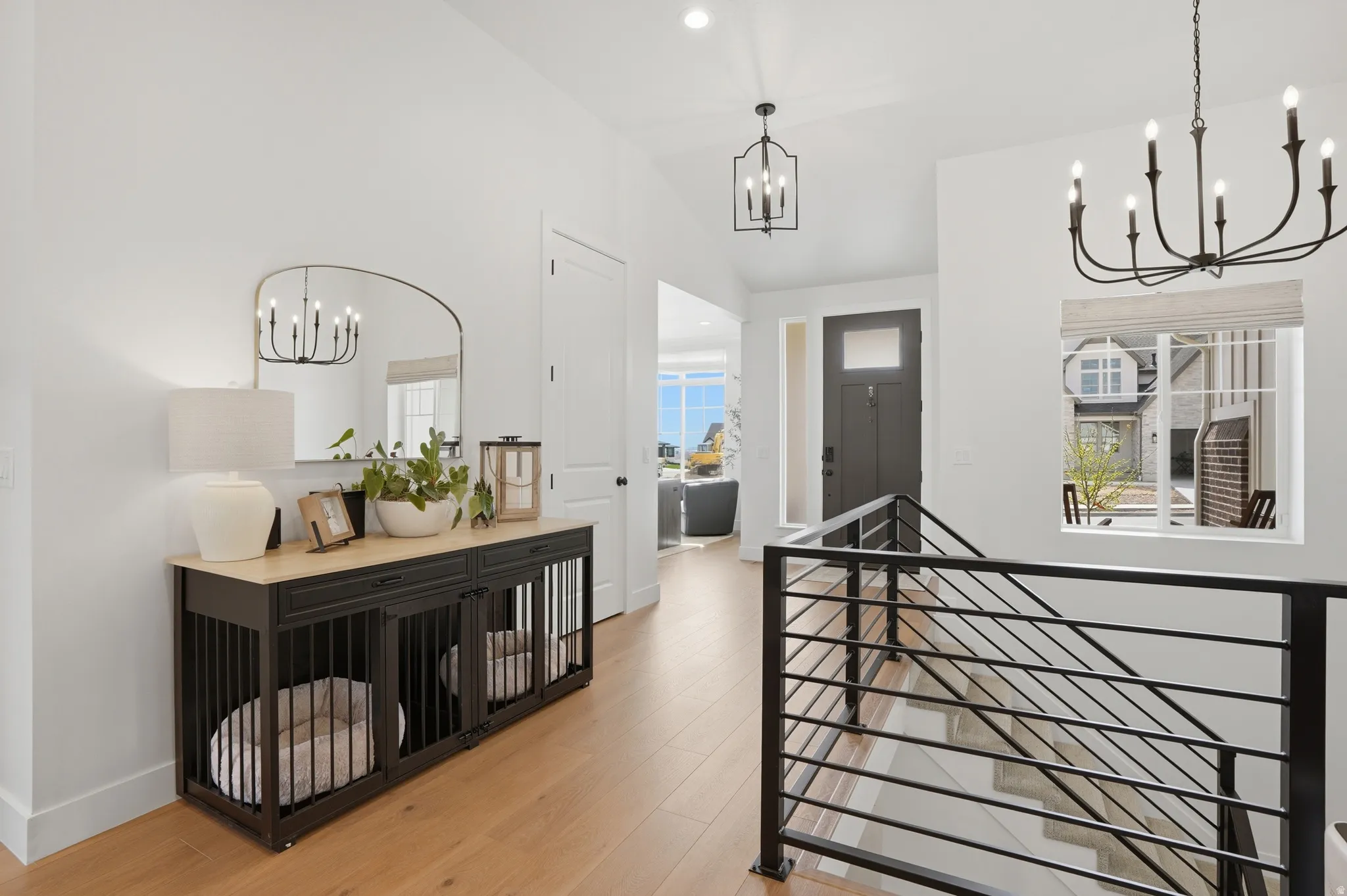 Corridor with suspended lighting, light wood-style flooring, an upstairs landing, and vaulted ceiling