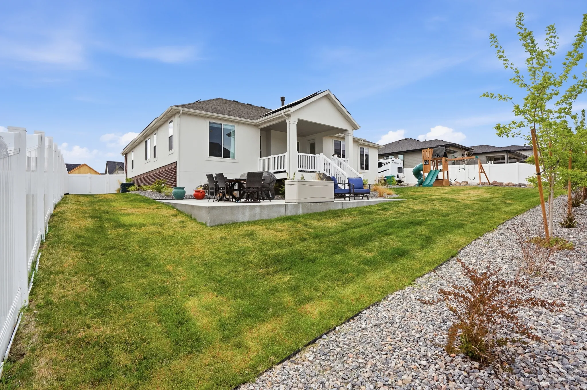 Rear view of property with a patio area, a fenced backyard, a playground, outdoor dining area, and stucco siding