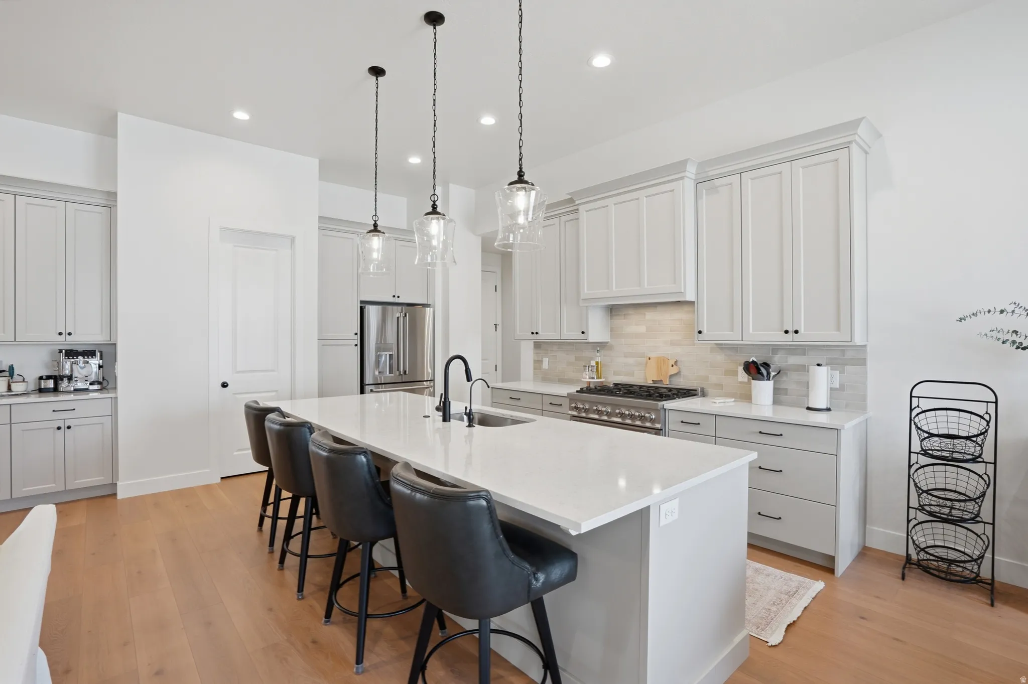 Kitchen with a center island with sink, high quality appliances, a breakfast bar, white cabinets, and light wood-type flooring