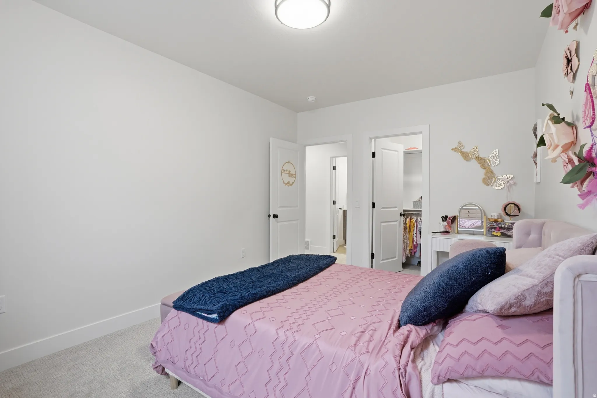 Bedroom with light colored carpet and a walk in closet