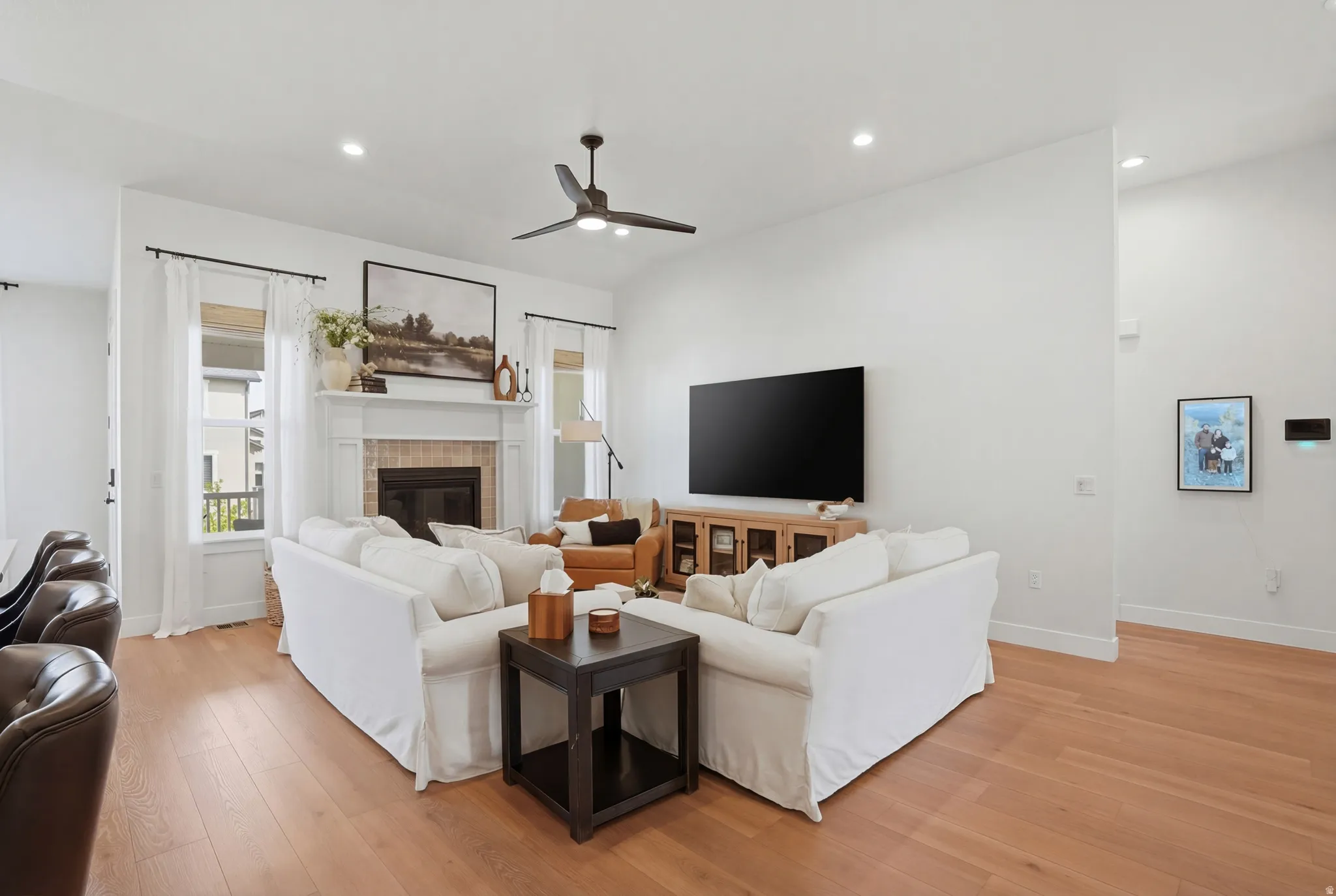 Living room featuring light wood-style floors, a ceiling fan, a fireplace, and recessed lighting