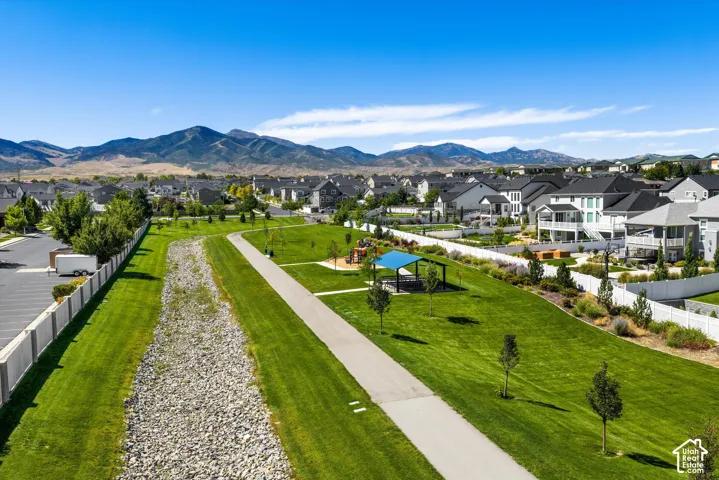 Expansive green space featuring a paved walking path, mature trees, and a covered pavilion