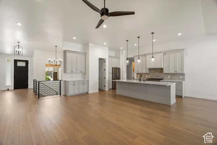 Spacious kitchen with light-toned cabinetry, a substantial kitchen island with a sink, and a tiled backsplash